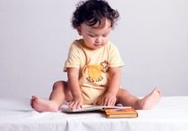 The child considers the children's book with pictures.