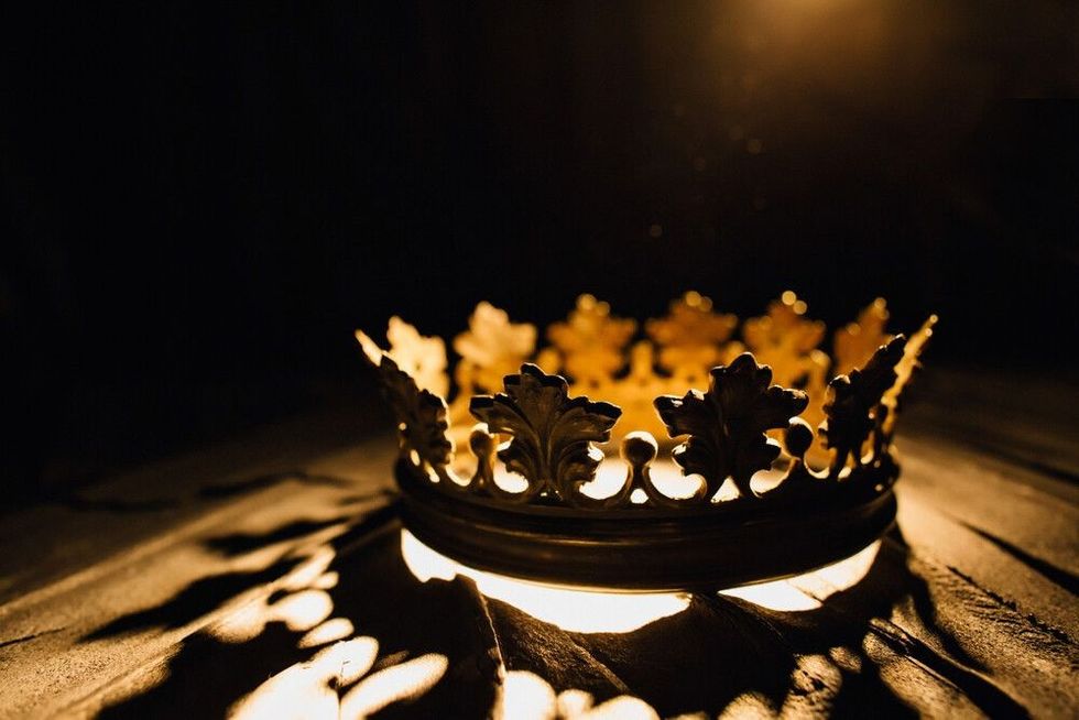 The crown on a black background is highlighted by a golden ray