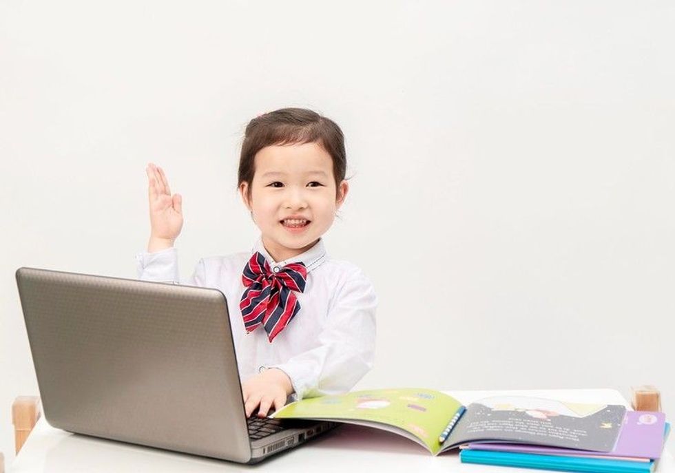 The little girl uses her laptop to surf the Internet for class