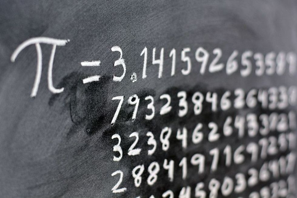 The number pi written with chalk on the blackboard, with its equivalence in numbers.