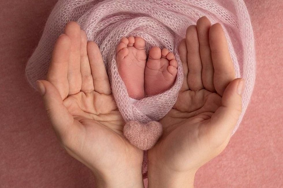 The palms of the mother are holding the foot