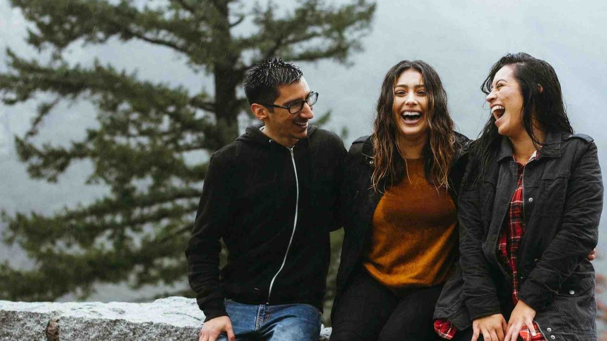 Three joyful friends sharing a beautiful moment of laughter amidst the serene beauty of a snowy forest.