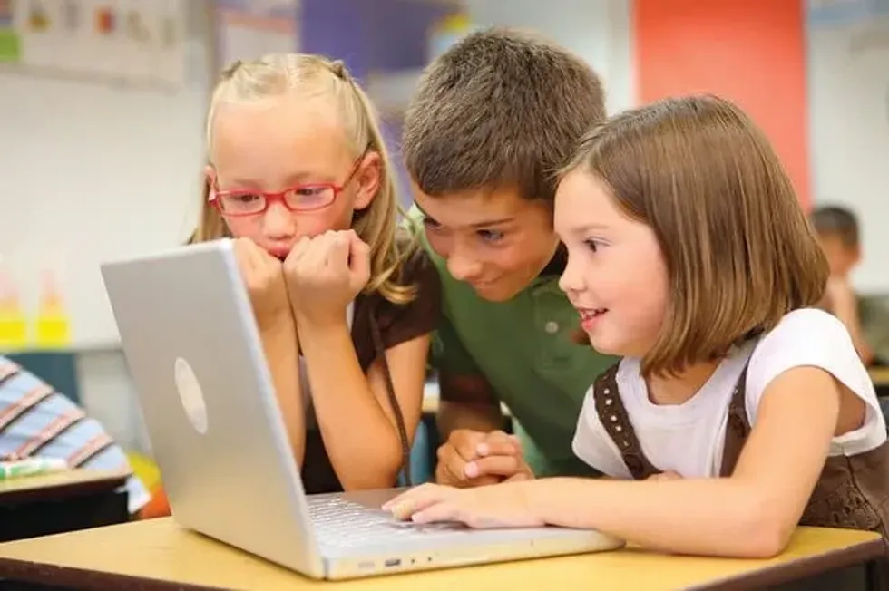 Three kids at a desk looking at a laptop to see a history timeline.