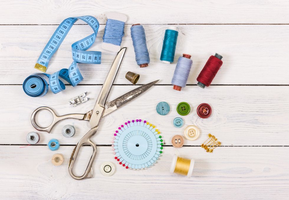 Tools and accessories for sewing on light wooden background.