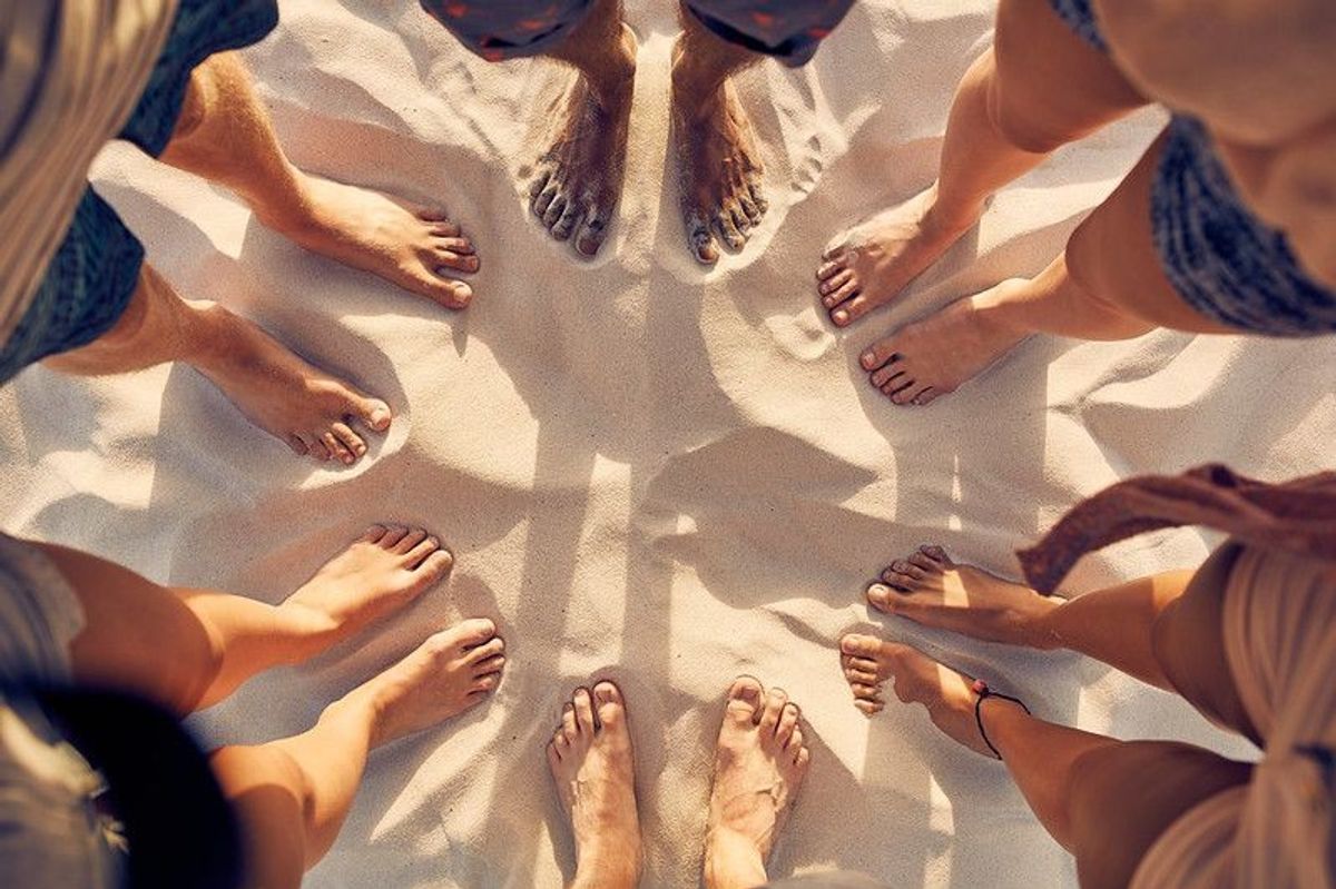 Top view image of feet of young people standing in a circle.