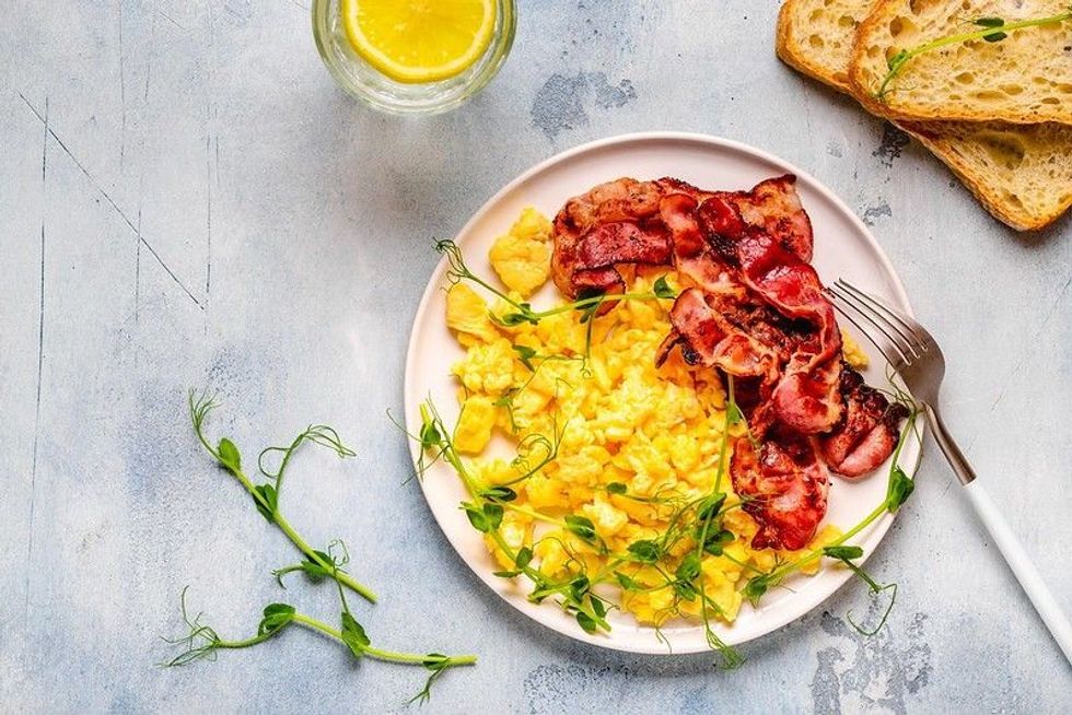 Traditional breakfast scrambled eggs with fried bacon.