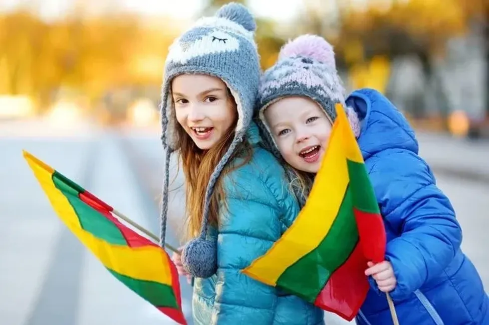 Two adorable little sisters holding tricolor Lithuanian flags