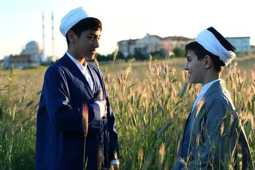 Two Arabic boys wearing traditional clothes standing in a field
