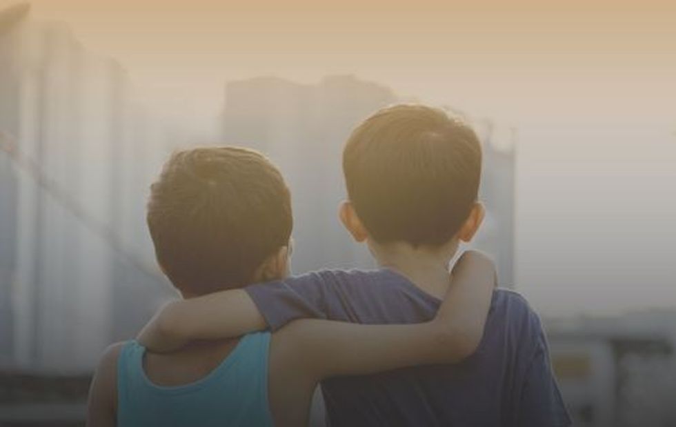 Two asian young brothers hugging each others over the sunset.