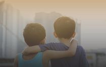 Two asian young brothers hugging each others over the sunset.