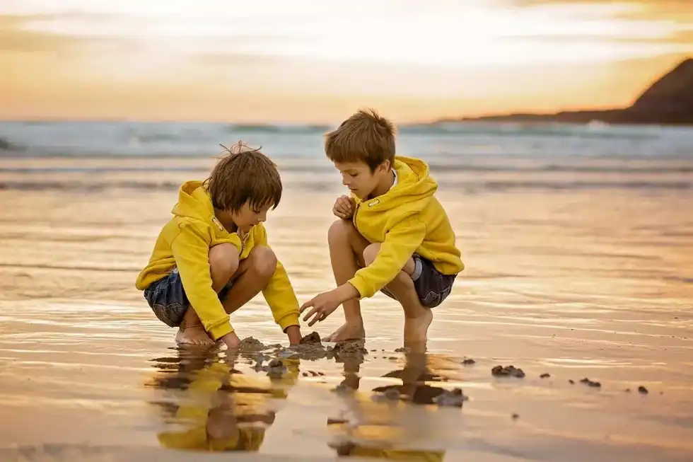 Two boys playing at the seaside on a cooler day.