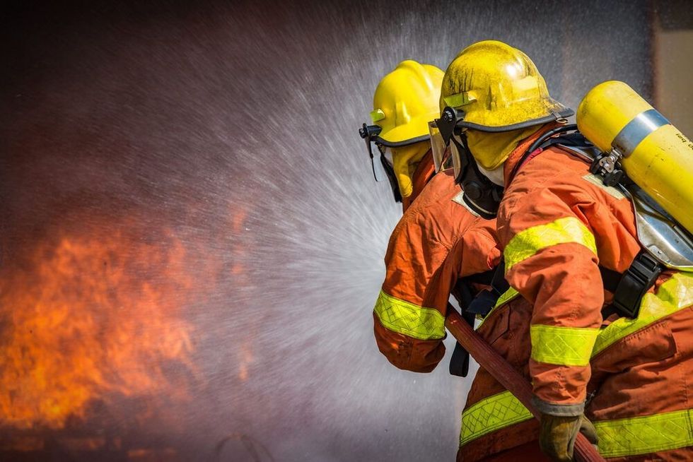 Two brave firefighters trying to blow out a fire