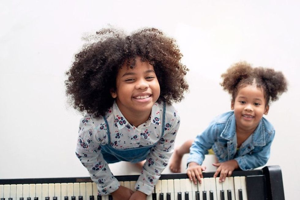 Two ethnic sisters playing keyboard musical instrument