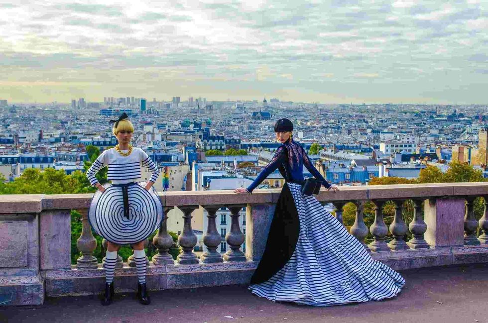 Two female models posing for the camera on a balcony showing the landscape view of a city