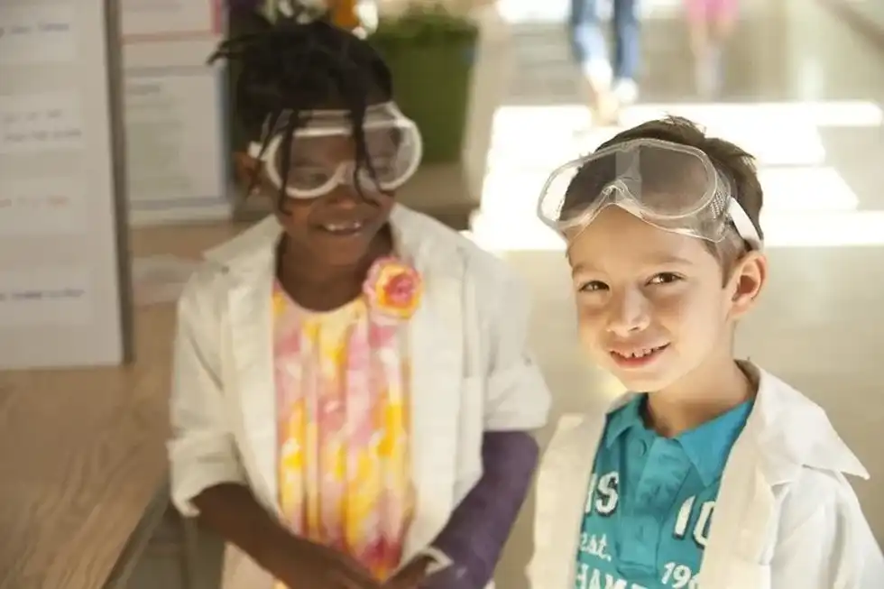 Two kids in lab coats and goggles ready to learn about the respiratory system in science class.