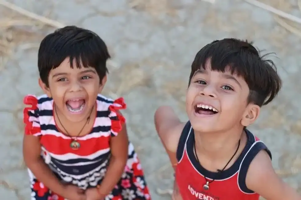 Two kids standing smiling and laughing at the best brain puns for kids.
