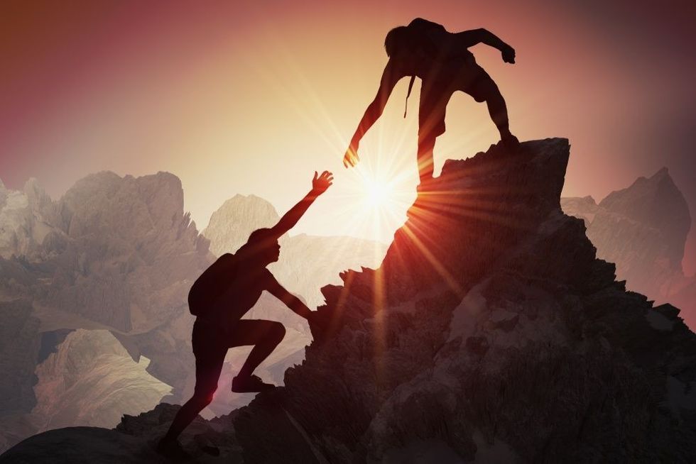 Two people climbing on mountain and helping.