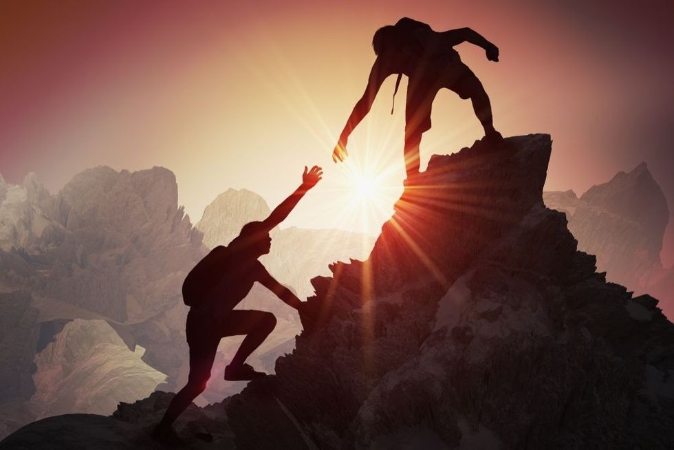 Two people climbing on mountain and helping.