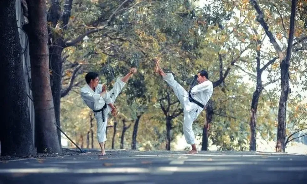 Two Taekwondo artists dressed in doboks, facing each other in a fighting stance.