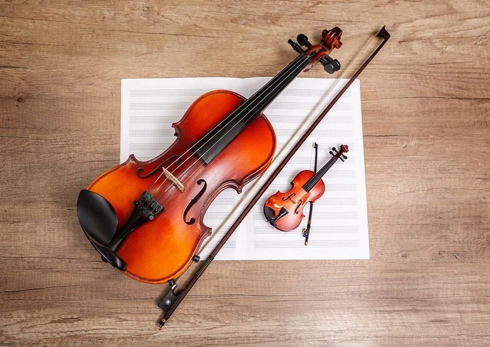 Two violins and a music book on a wooden table
