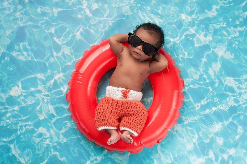 Two week old newborn baby boy sleeping on a tiny inflatable swim ring