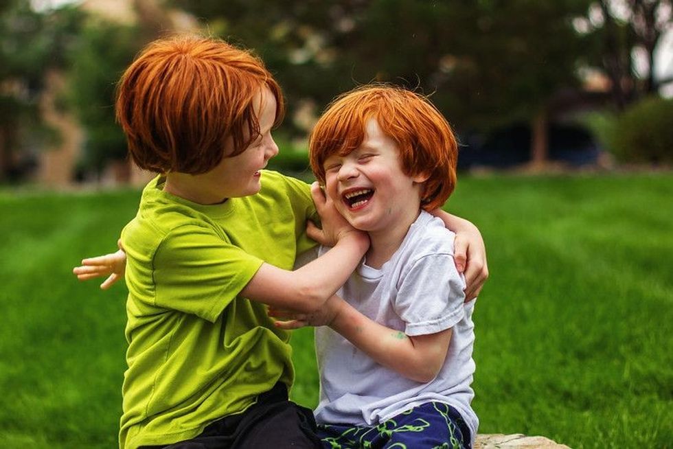 Two young brothers with natural red hair playing outdoor together