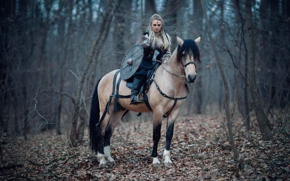 Viking warrior female sitting on a horse in forest