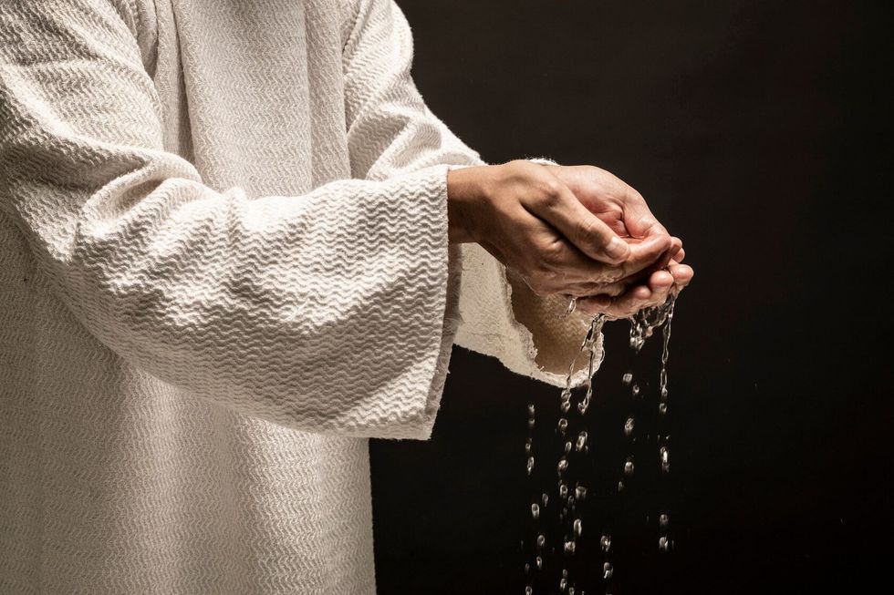 Water for Baptism pouring out of the hands of a person