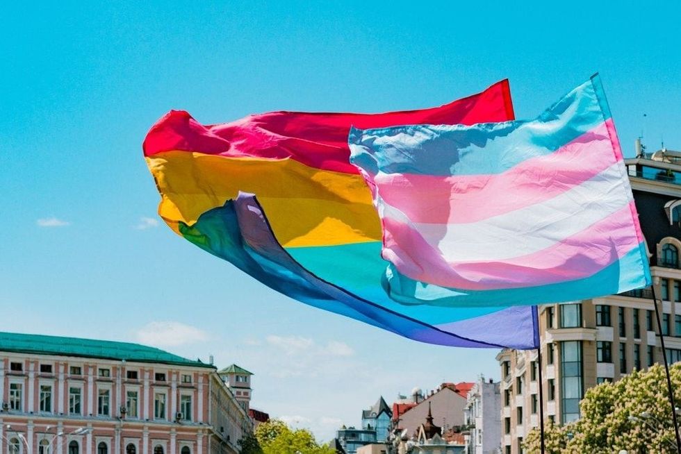 Waving transgender and gay rainbow LGBT flags.