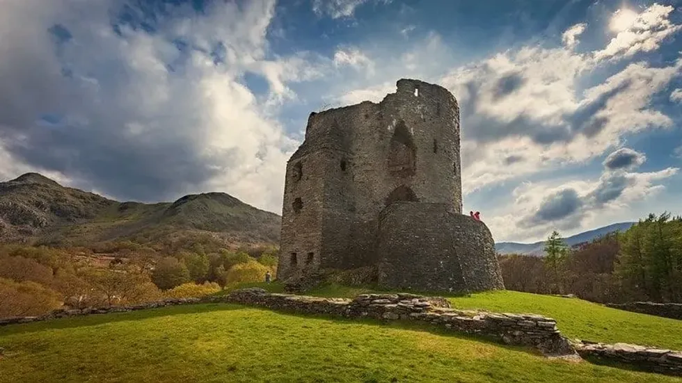 Welsh Castle in the countryside with hills in the background on a sunny day.