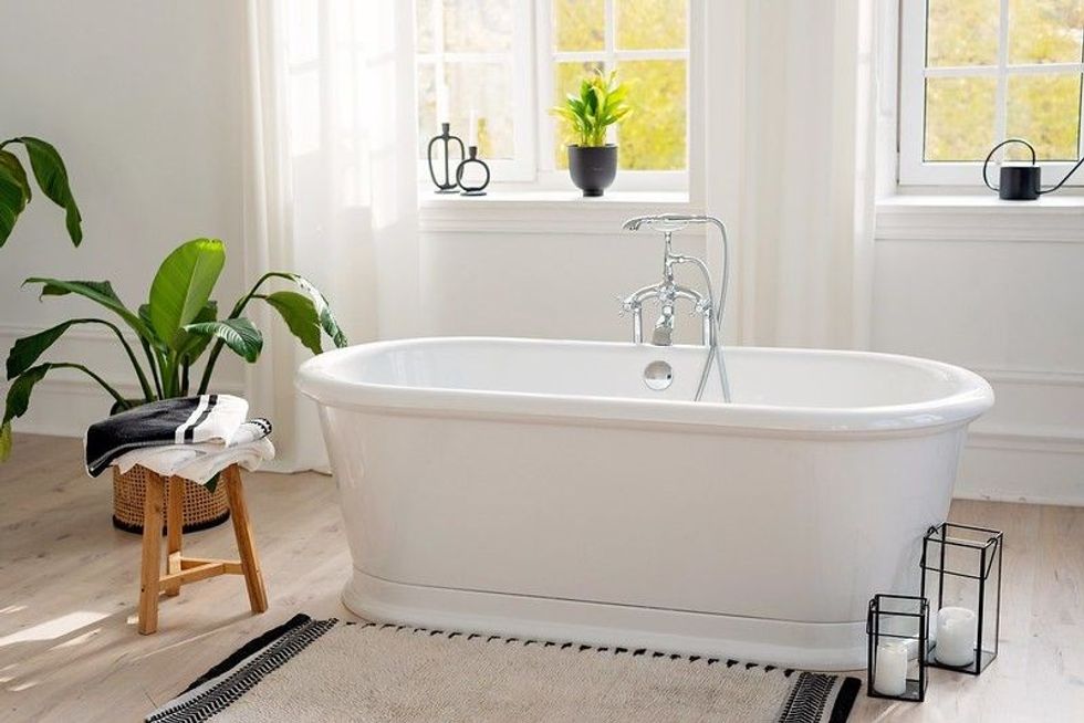 White bathtub on a wooden floor in a bright room