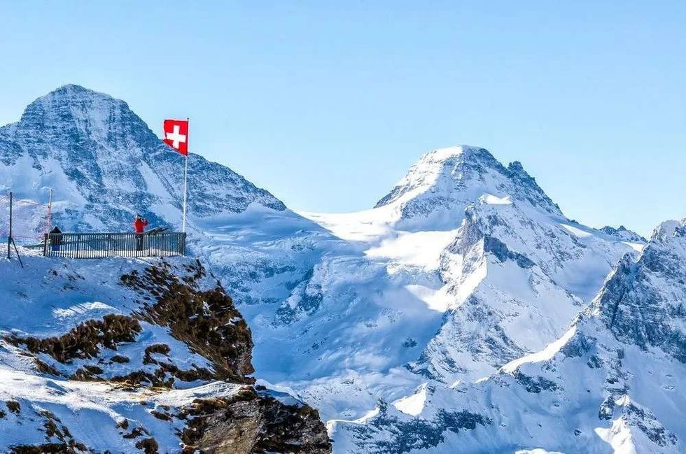 White mountain caps with waving flag of Switzerland