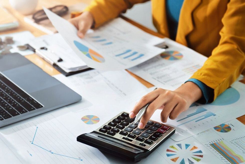 Woman accountant use calculator and computer with holding pen 