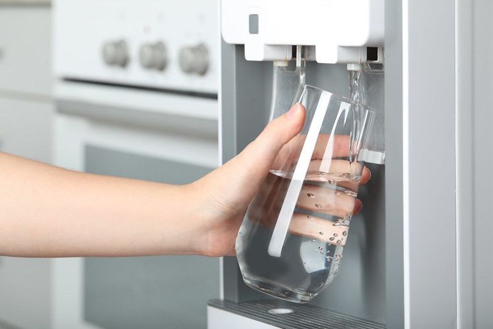 Woman filling glass from water cooler.