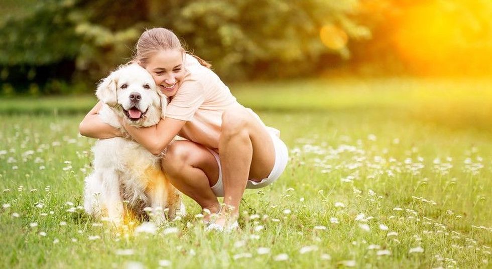 Woman hugs and cuddles Golden Retriever dog and pets him with love.