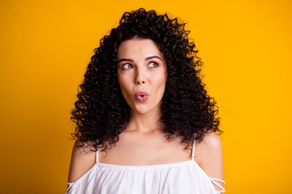 Woman looking around whistling isolated on color background