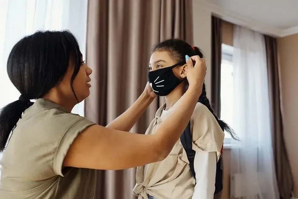 woman putting a fun COVID face mask onto her child