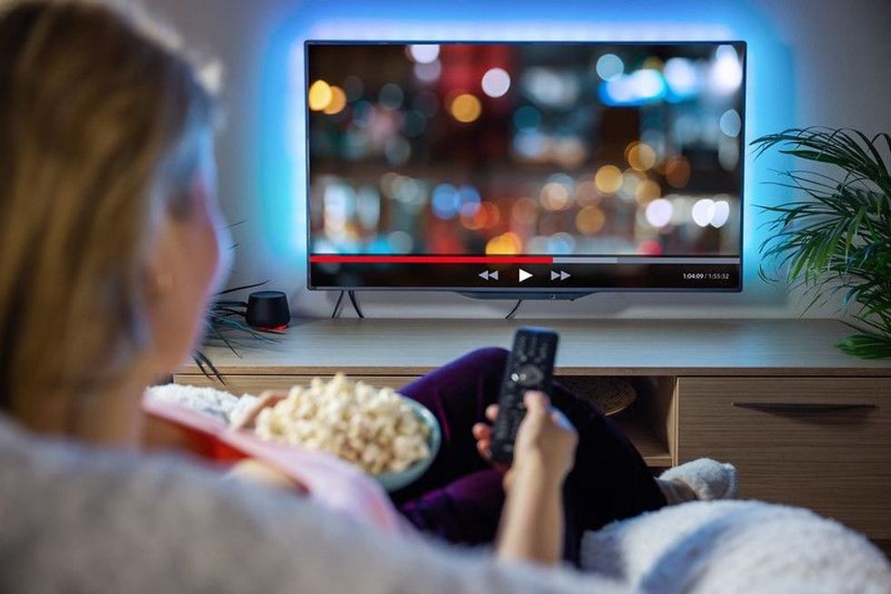 Woman relaxing at home in evening and watching TV.