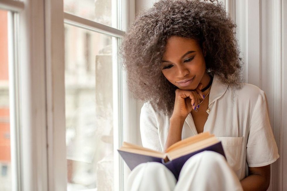 Woman sitting on a windowsill reading a book