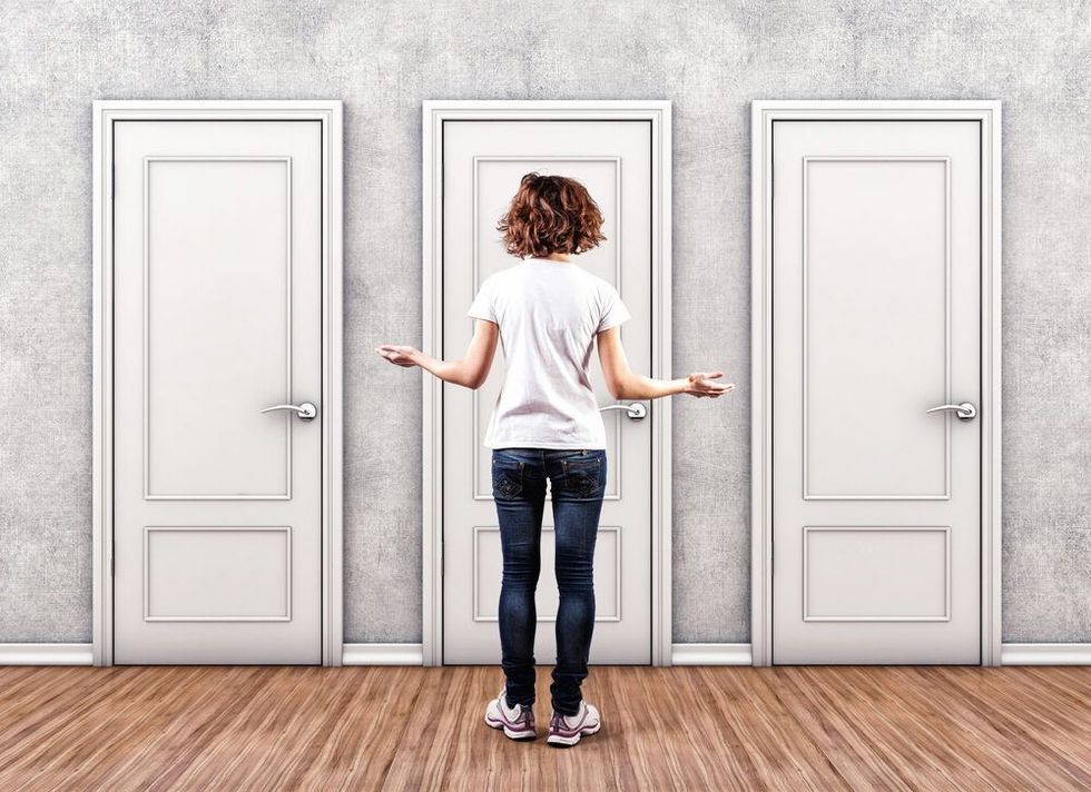 Woman standing in front of three doors trying to decide which one to go through