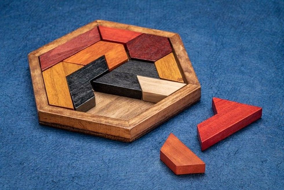 wooden hexagon tangram puzzle against textured handmade bark paper