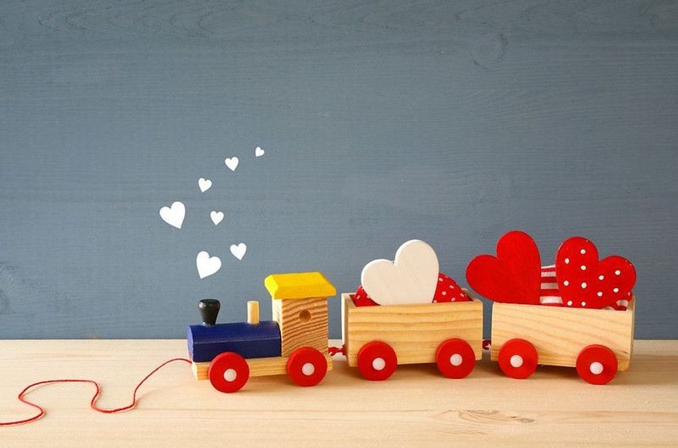 Wooden toy train with hearts on the table.