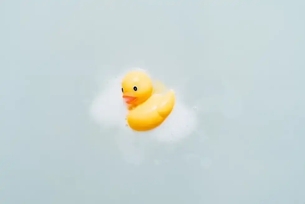 Yellow rubber duck with soapy foam on it.