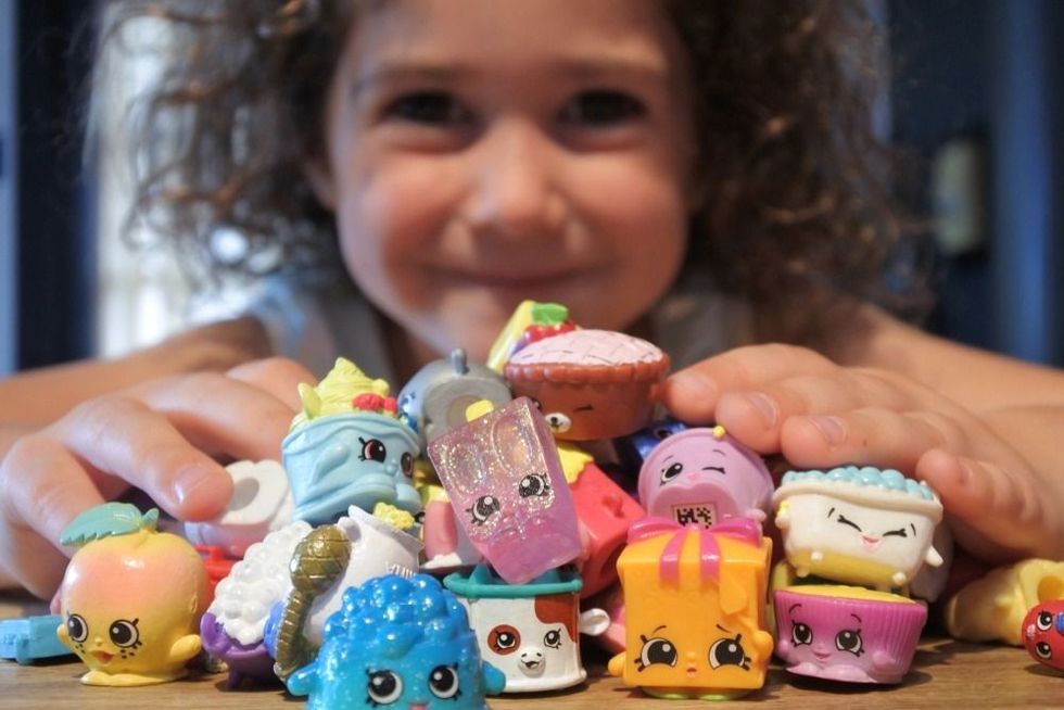 Young Australian girl holding Shopkins a range of tiny collectable toys manufactured by Moose Toys.Each plastic figure has a recognizable face and unique name.