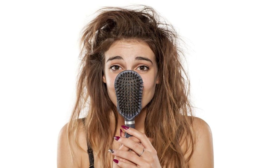 young beautiful woman with messy hair poses with hairbrush