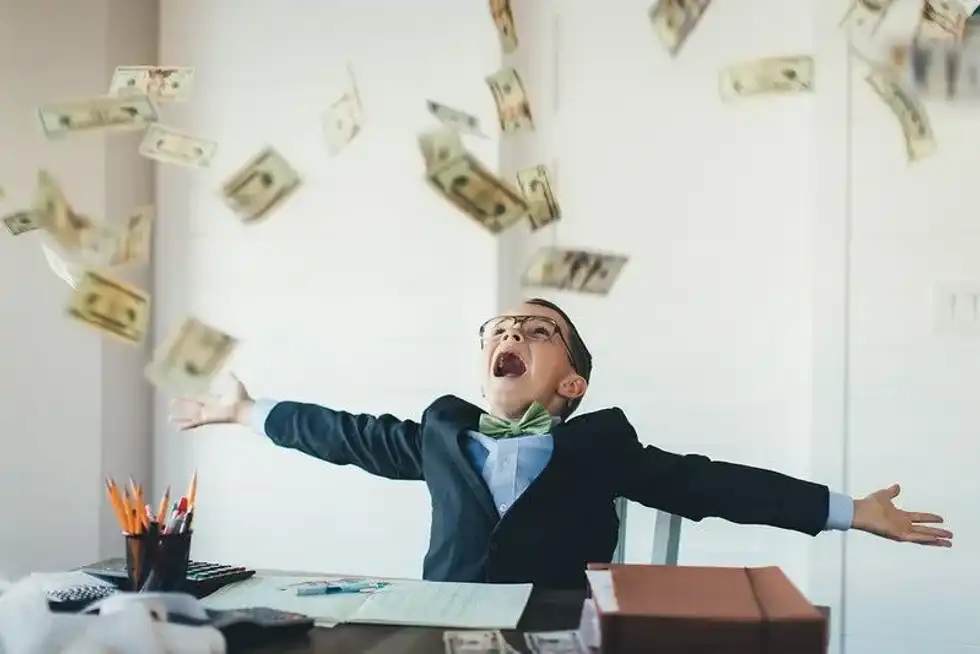 Young boy being showered in dollar bills.