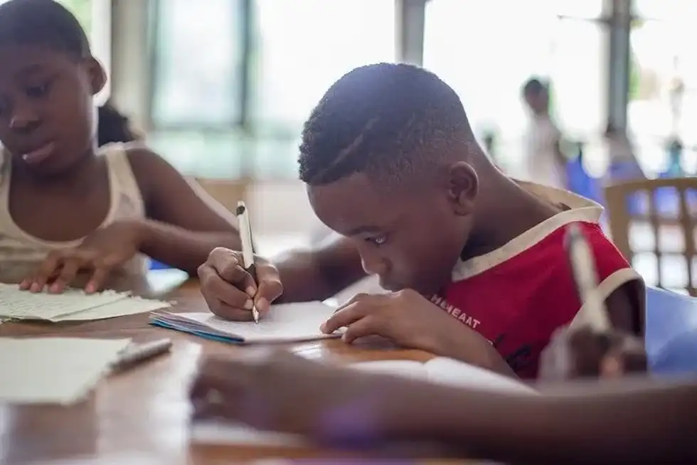 Young boy sat at his desk learning about multi-clause sentences.