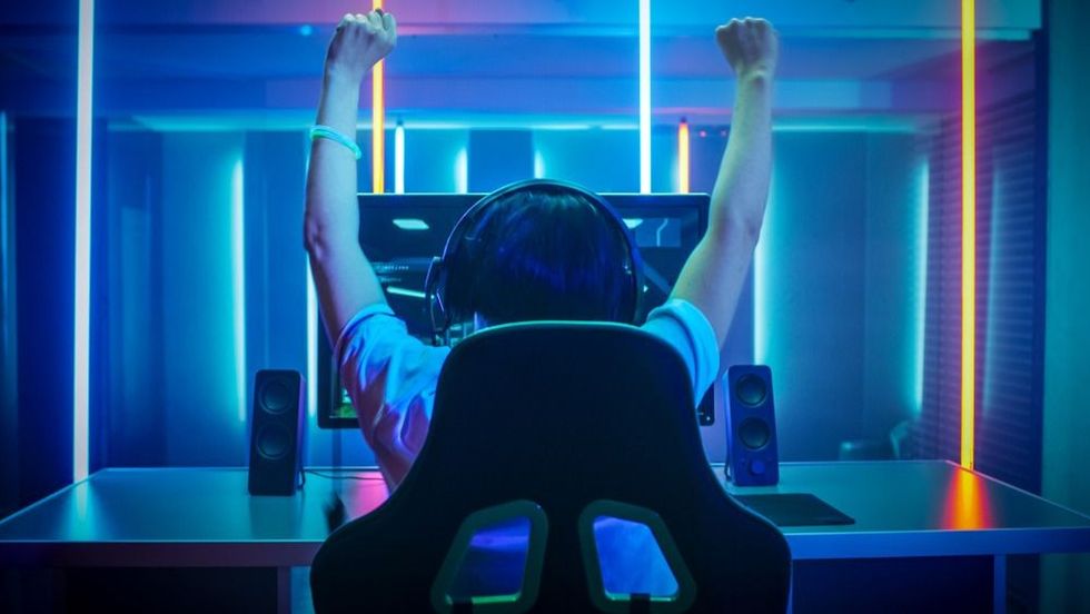 Young boy wearing headphones celebrating success while playing video games
