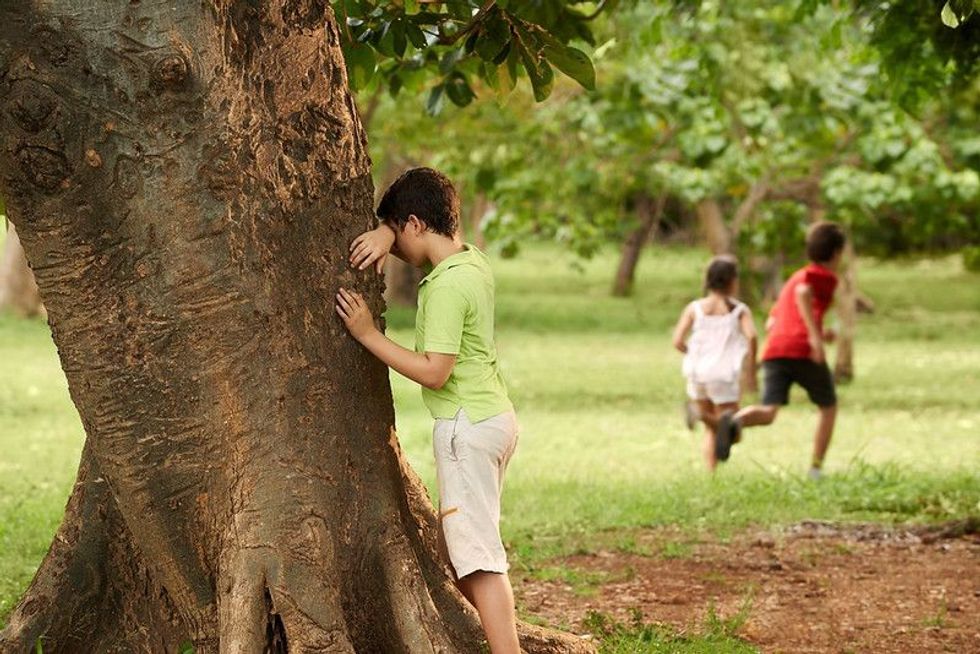 Young boys and girls playing hide and seek in park