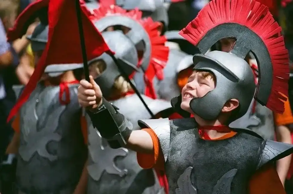 Young boys dressed up as Roman soldiers wearing armour and helmets.